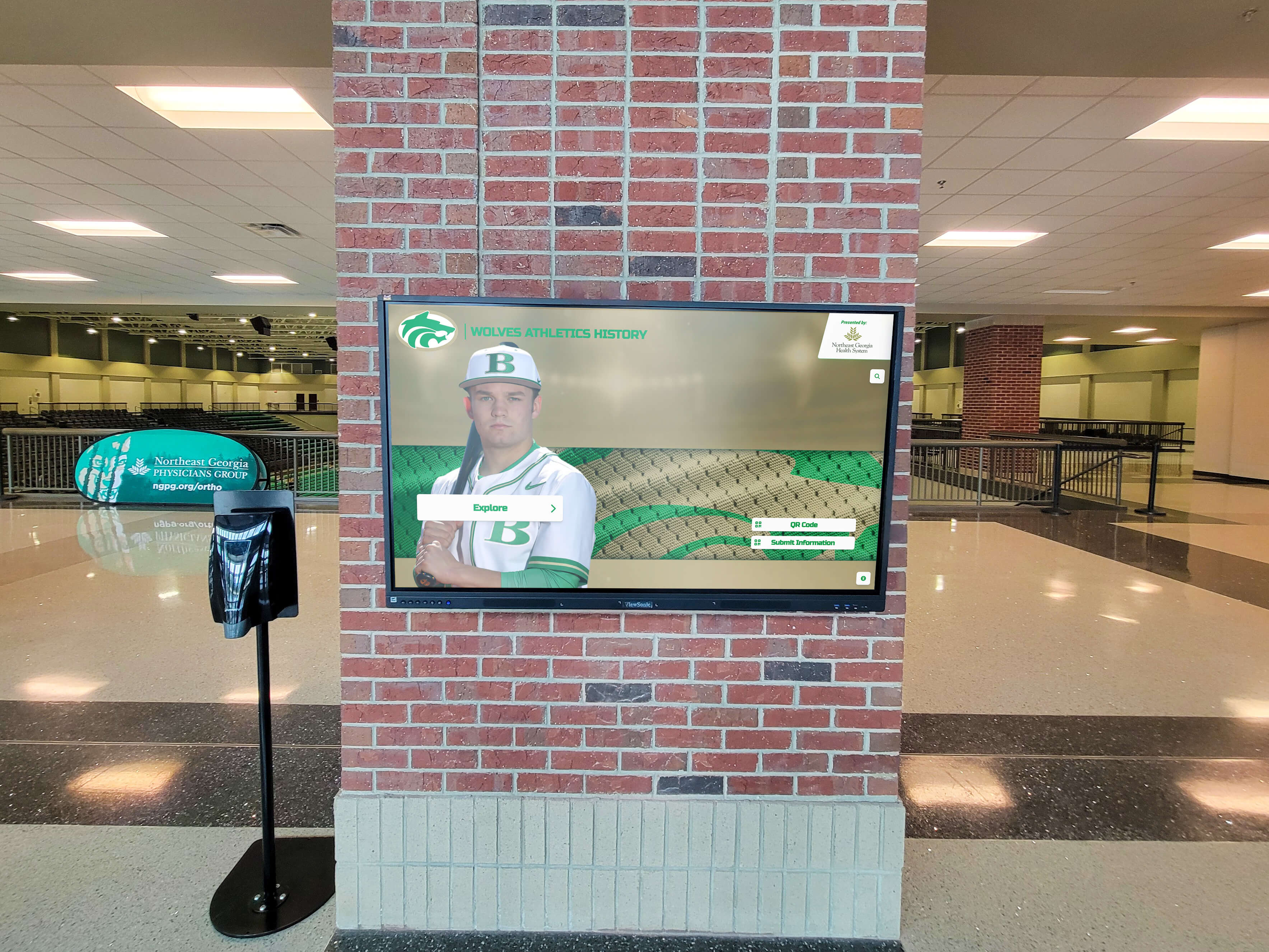 Digital display featuring a baseball player on a brick pillar in an arena lobby — permanent player recognition installed alongside architectural elements