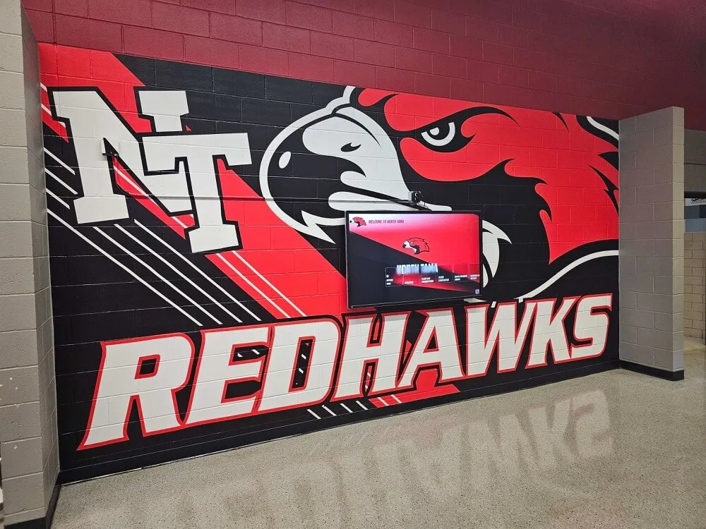 Redhawks mural in school hallway with TV screen