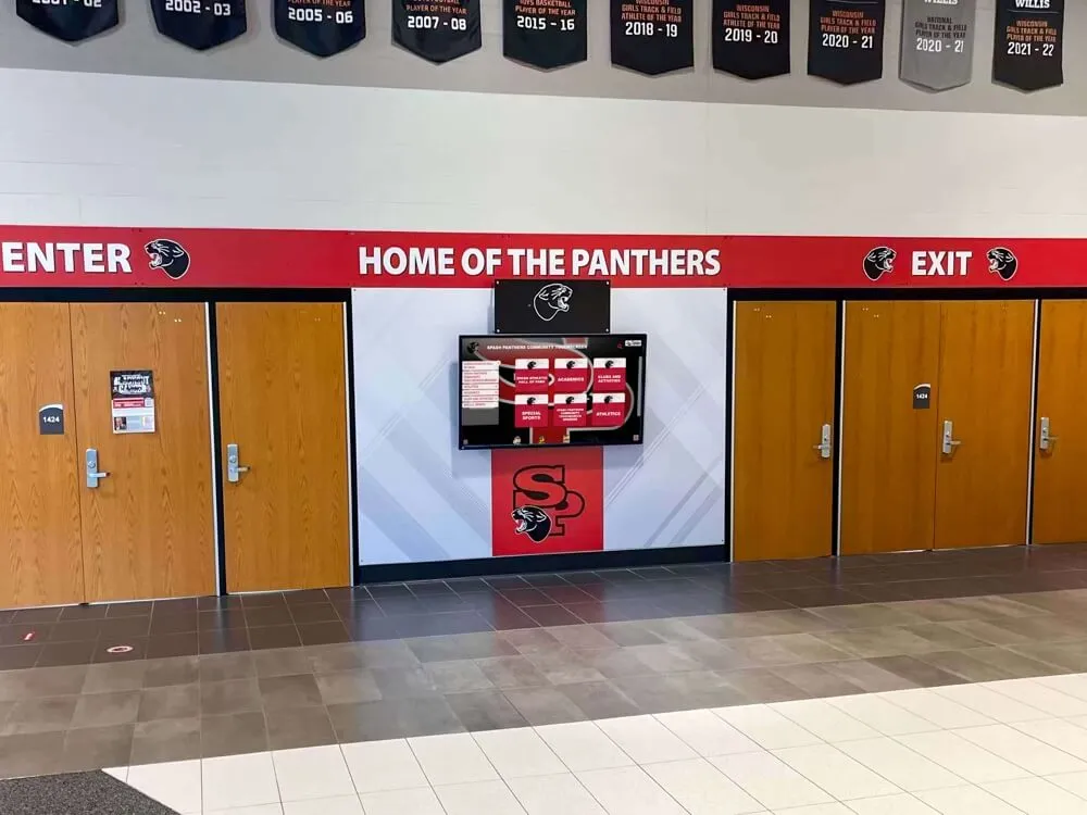 School hallway with Home of the Panthers signage and digital recognition screen School hallway home of the panthers with wooden doors and digital recognition screen