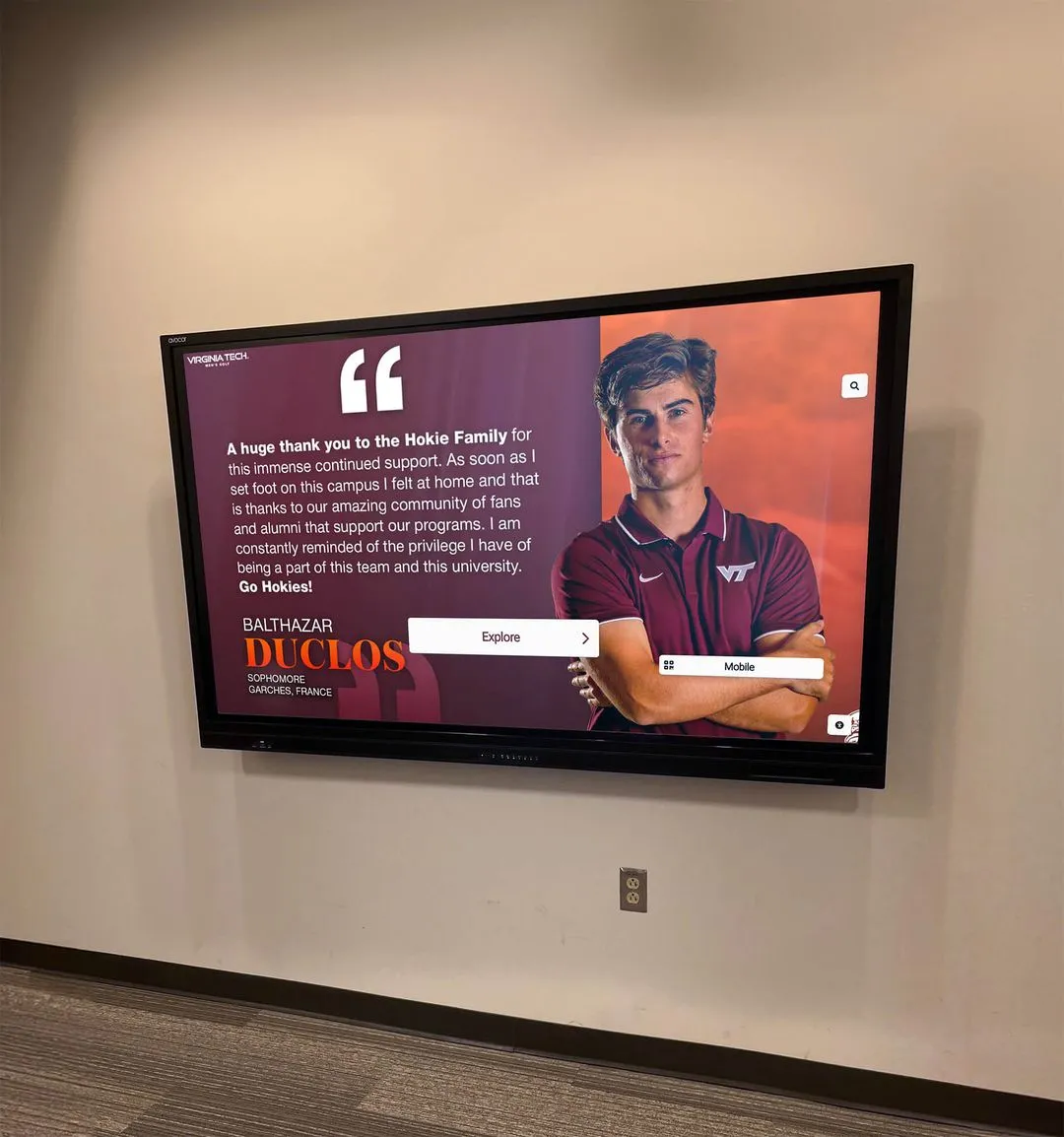 Virginia Tech digital hall of fame wall display with student-athlete in maroon polo interacting with recognition content