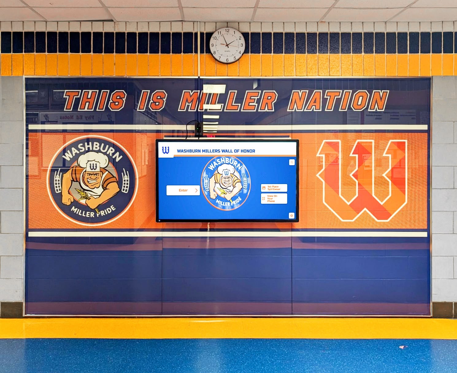 Digital wall of honor display in school hallway celebrating student recognition milestones Washburn Millers wall of honor with digital screen in school hallway